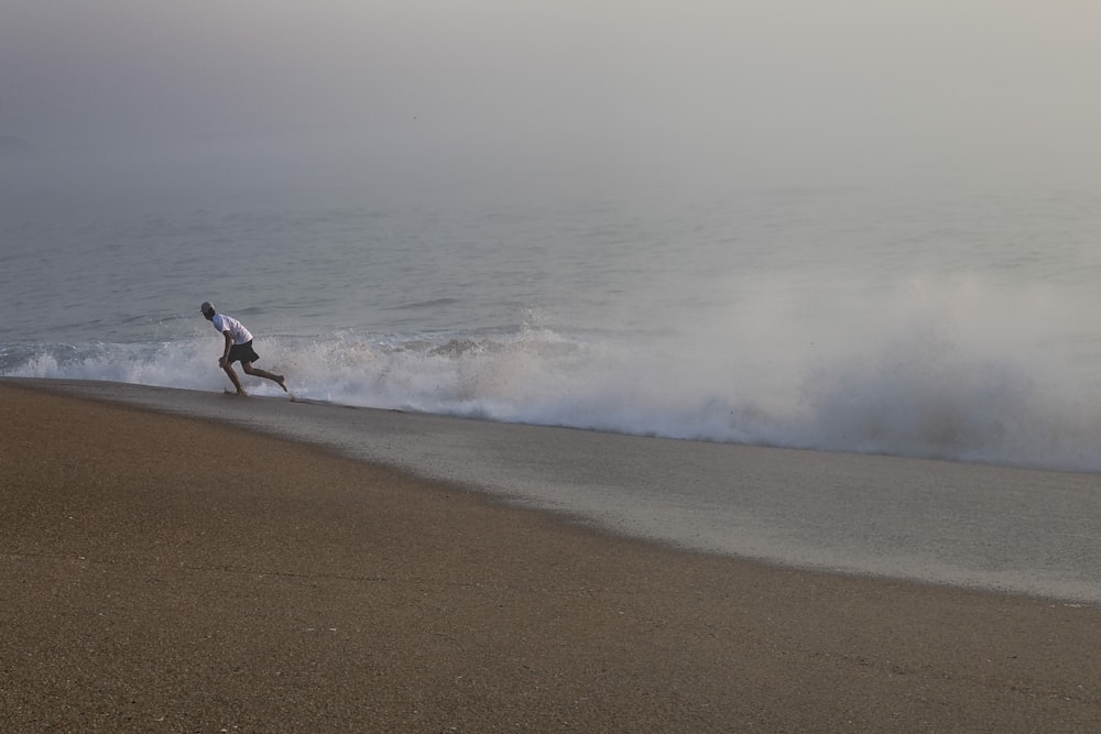 a man running on the beach with a surfboard