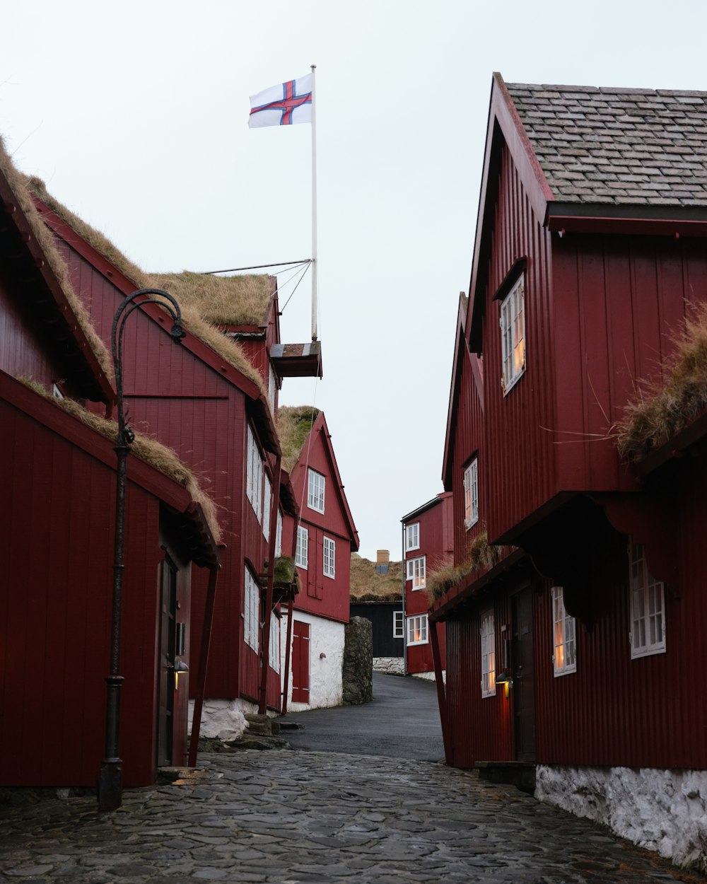 uma rua de paralelepípedos com edifícios vermelhos e uma bandeira em um poste