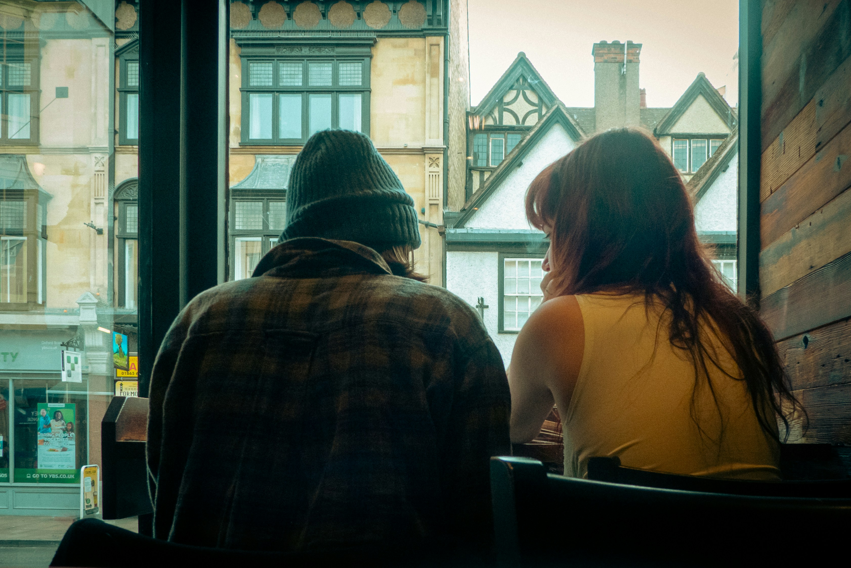 A man and woman sitting across from each other at a table by a window