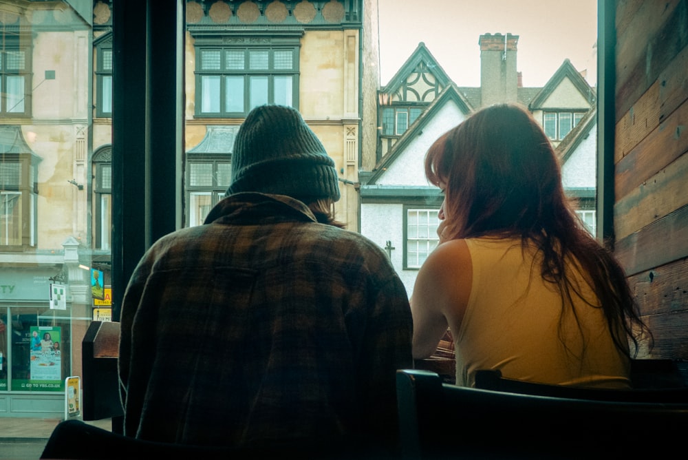 a man and a woman sitting at a table looking out a window