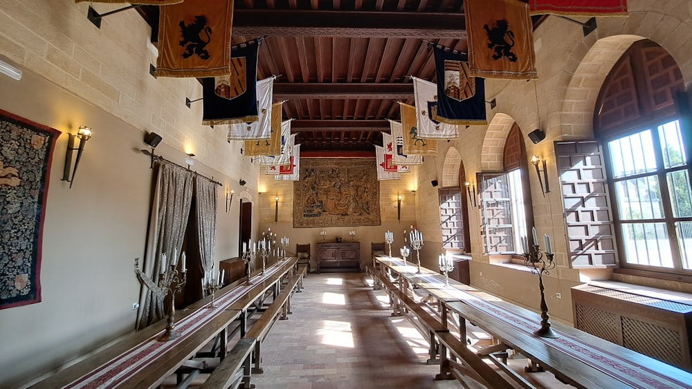 a long room with benches and a tapestry hanging from the ceiling