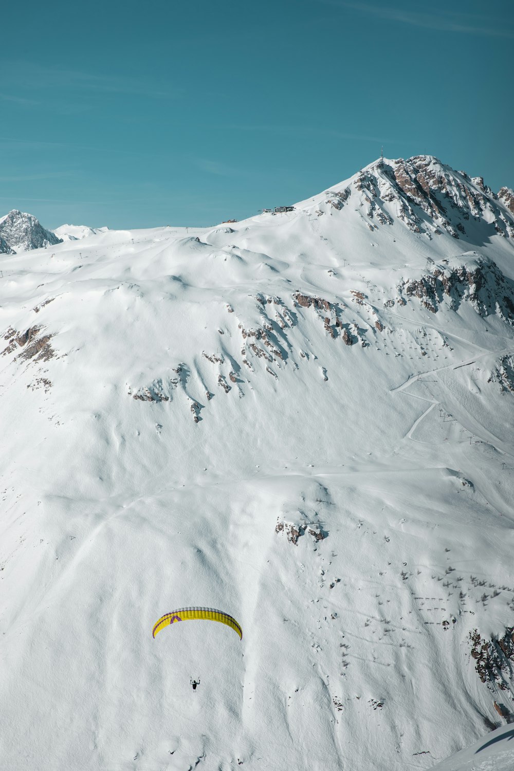 a paraglider flying over a snow covered mountain