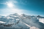 the sun is shining over a snowy mountain range
