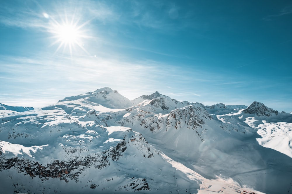 the sun is shining over a snowy mountain range