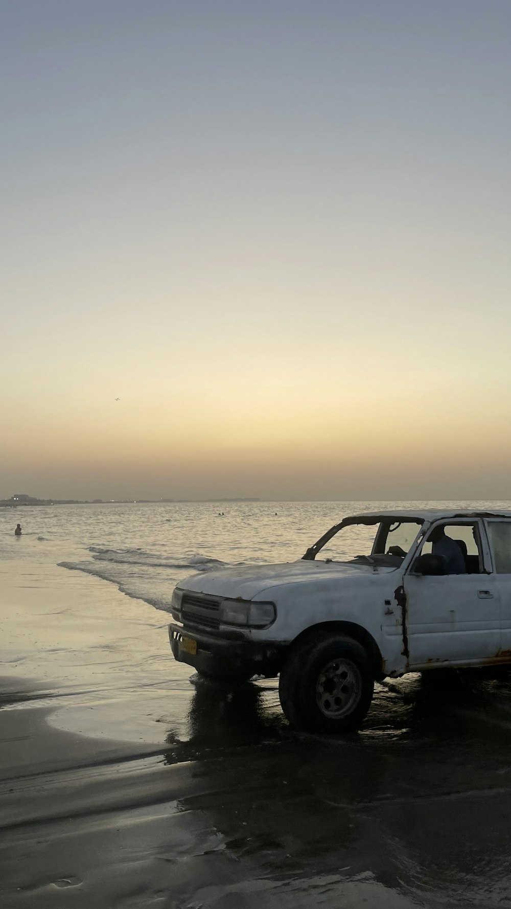a truck is parked on the beach near the water
