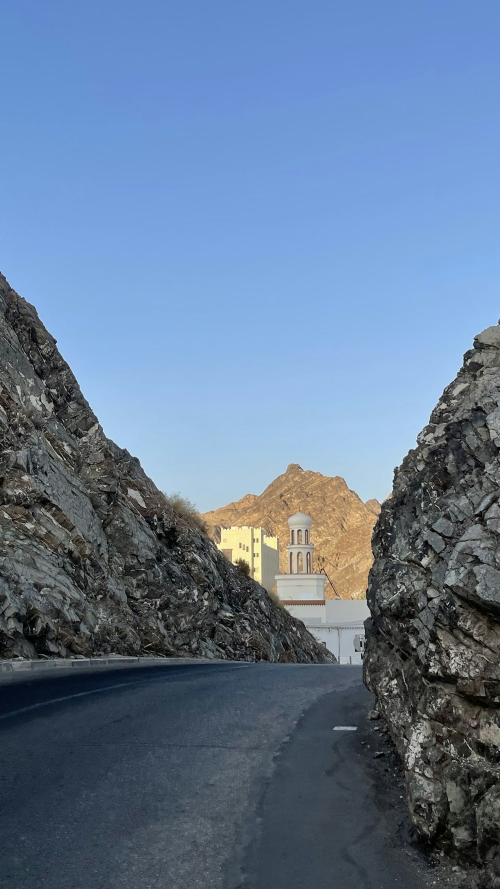 a view of a mountain road with a building in the distance