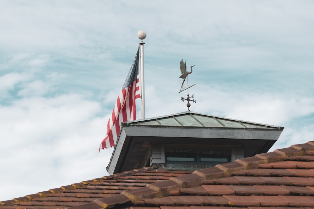 an american flag and a weather vane on top of a roof