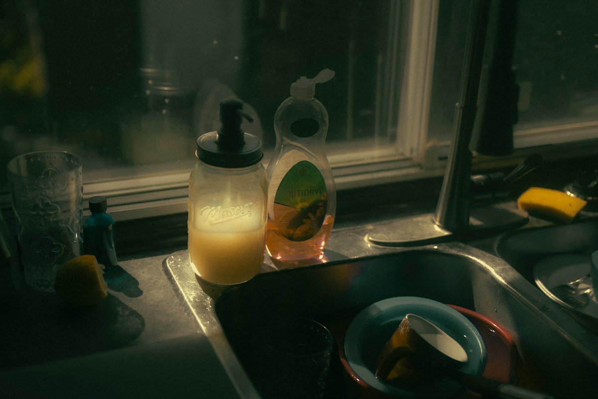 Cleaning bottles lined up on a kitchen windowsill