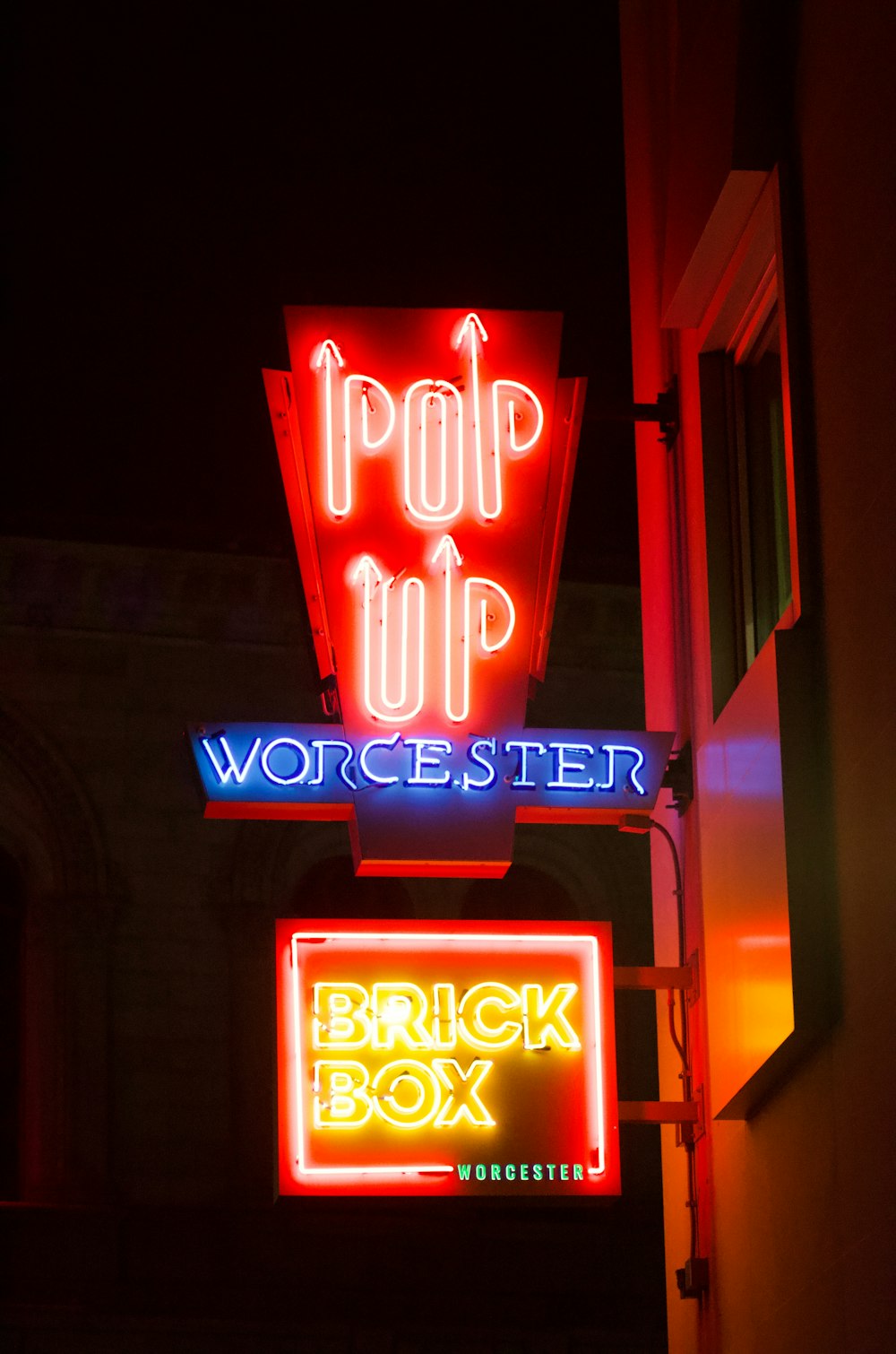 a couple of neon signs that are on the side of a building