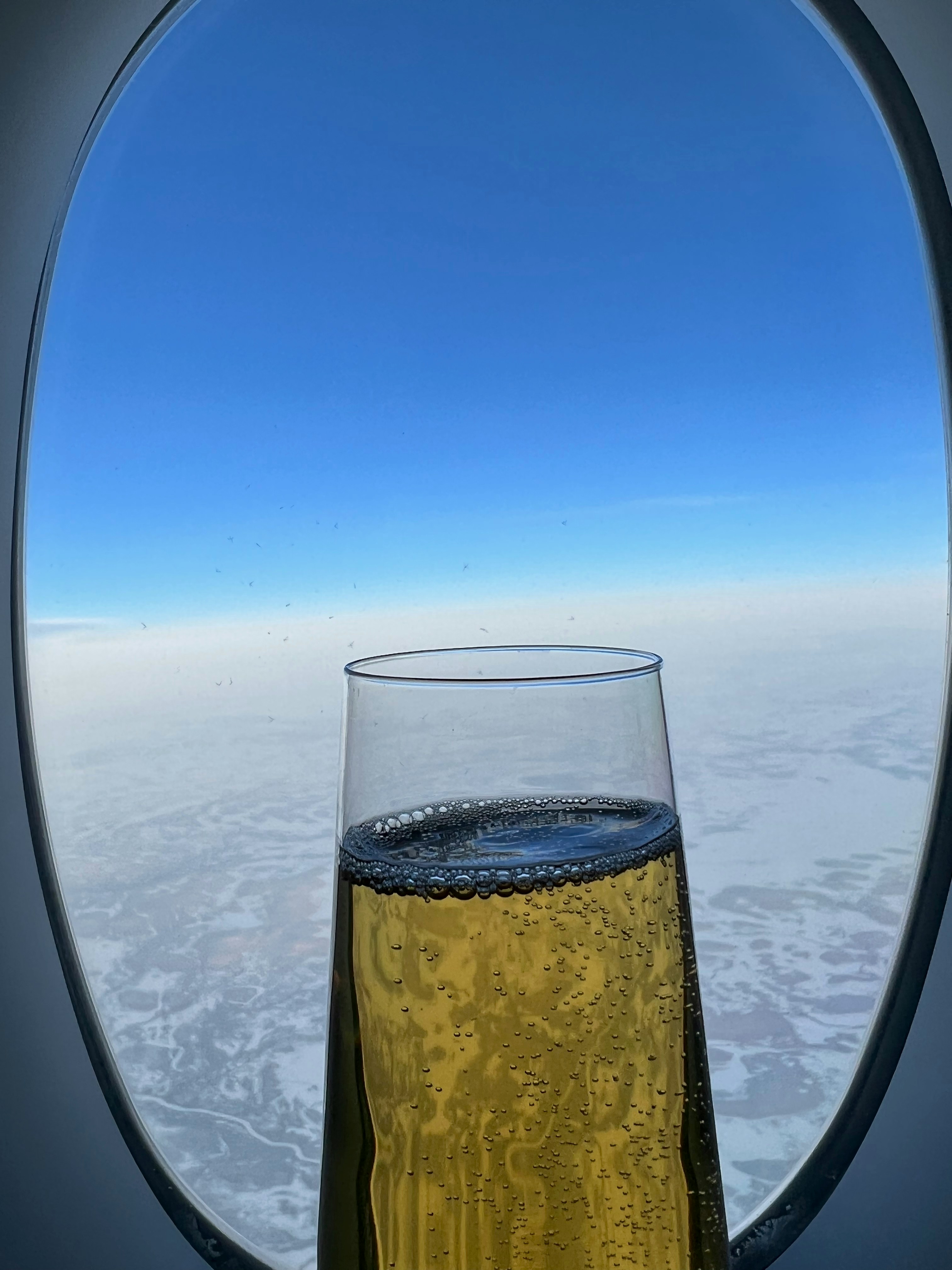 Business class airplane seat with champagne glass and city view through window