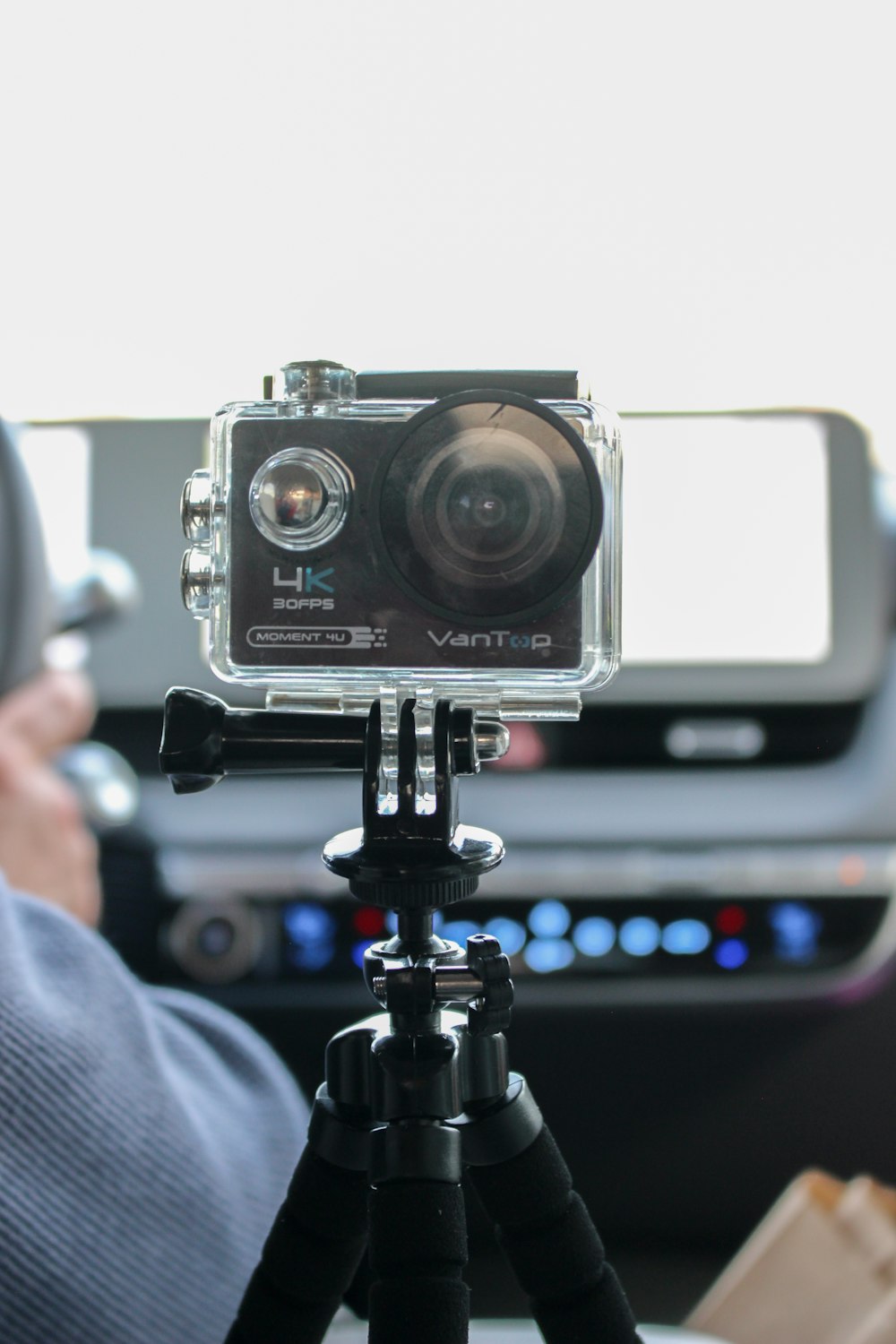a person holding a camera in front of a car
