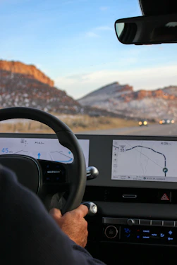 a man driving a car with a mountain in the background