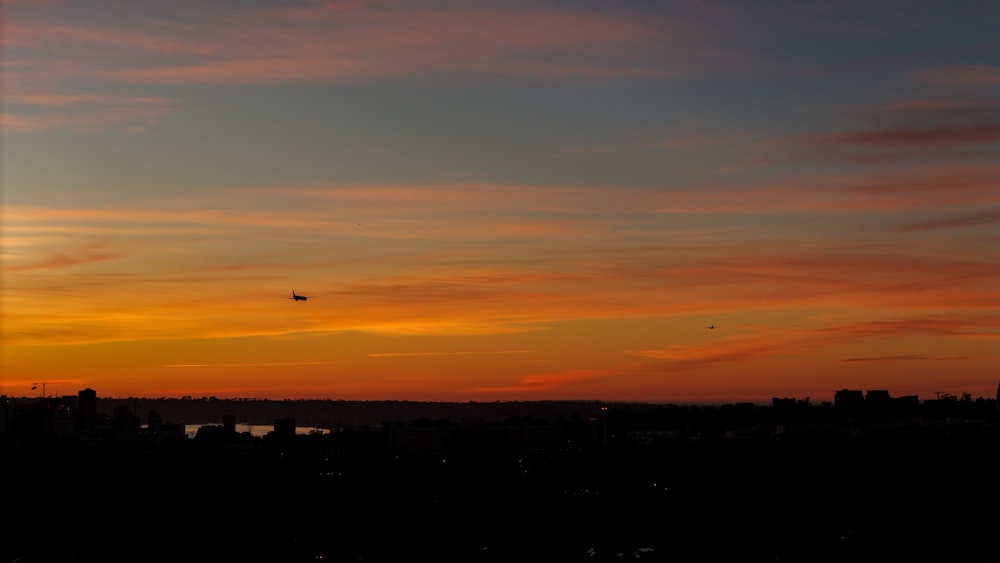 a sunset with a plane flying in the distance