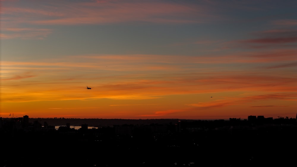 un tramonto con un aereo che vola in lontananza