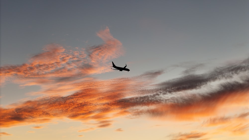ein Flugzeug, das bei Sonnenuntergang am Himmel fliegt