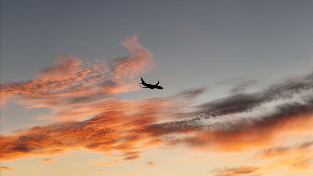 a plane flying in the sky at sunset