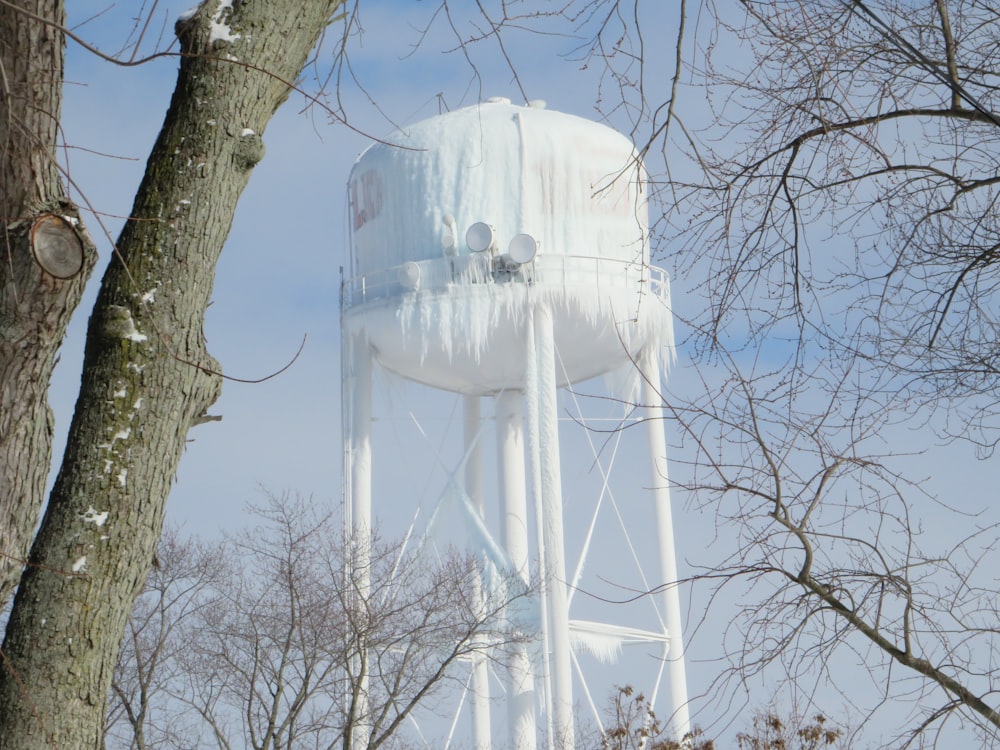 a tall white water tower sitting next to a tree
