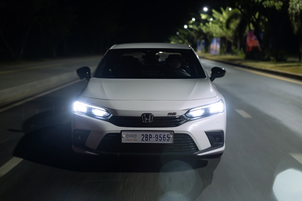 a white car driving down a street at night