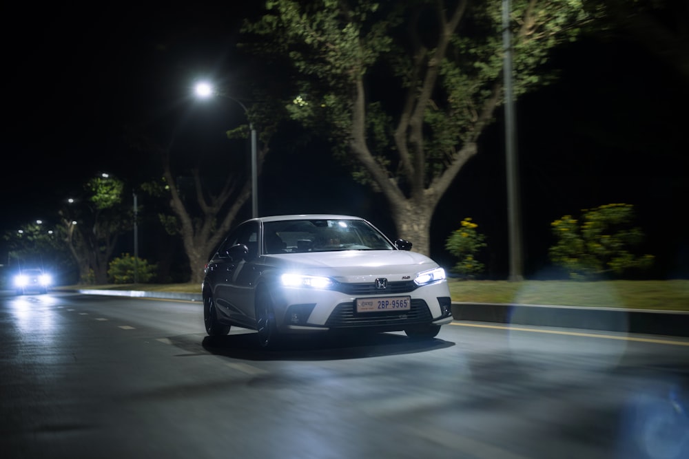 a white car driving down a street at night