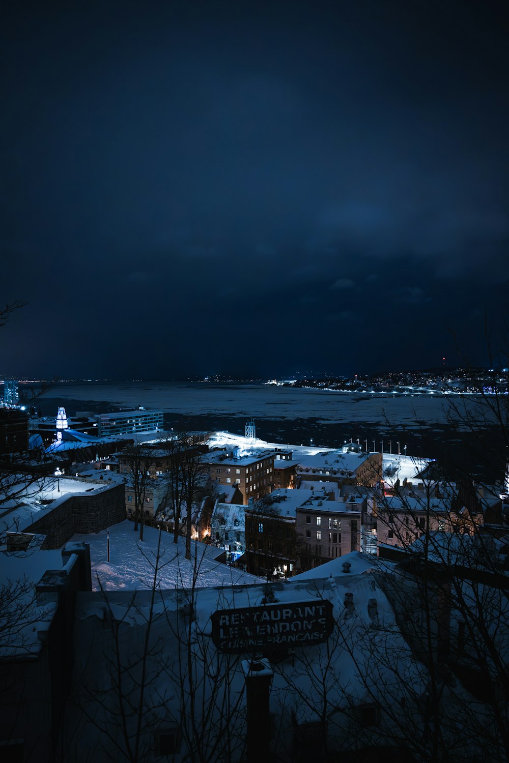 uma vista noturna de uma cidade com neve no chão