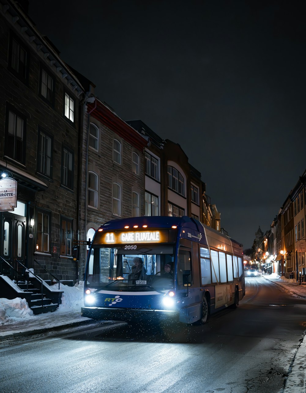 a bus driving down a snowy street at night