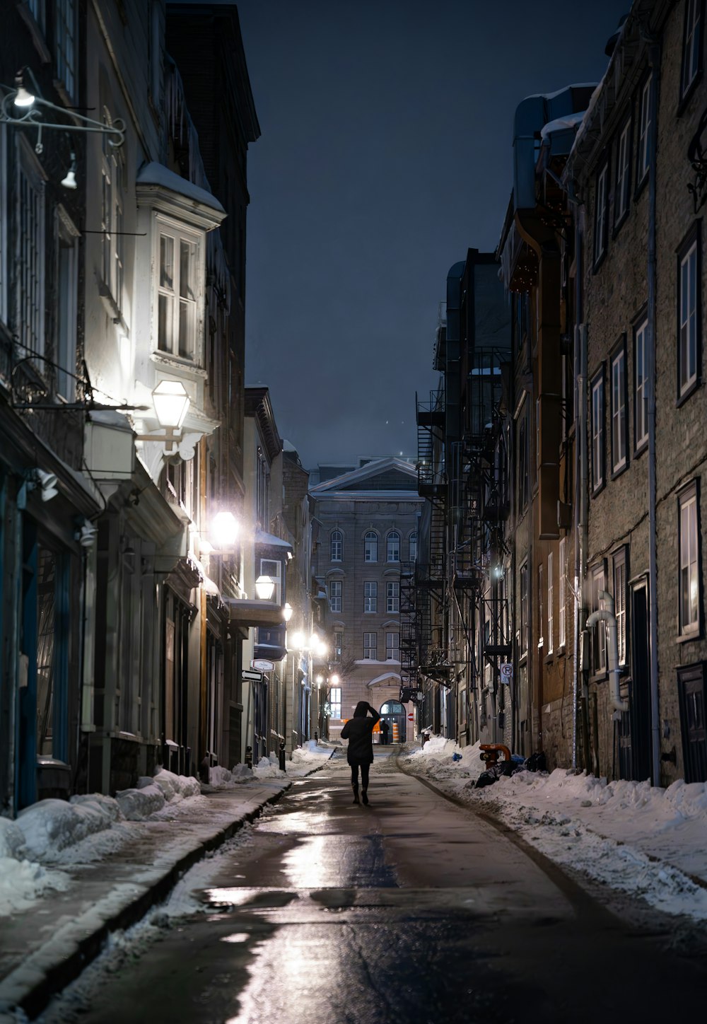 a couple of people walking down a snow covered street