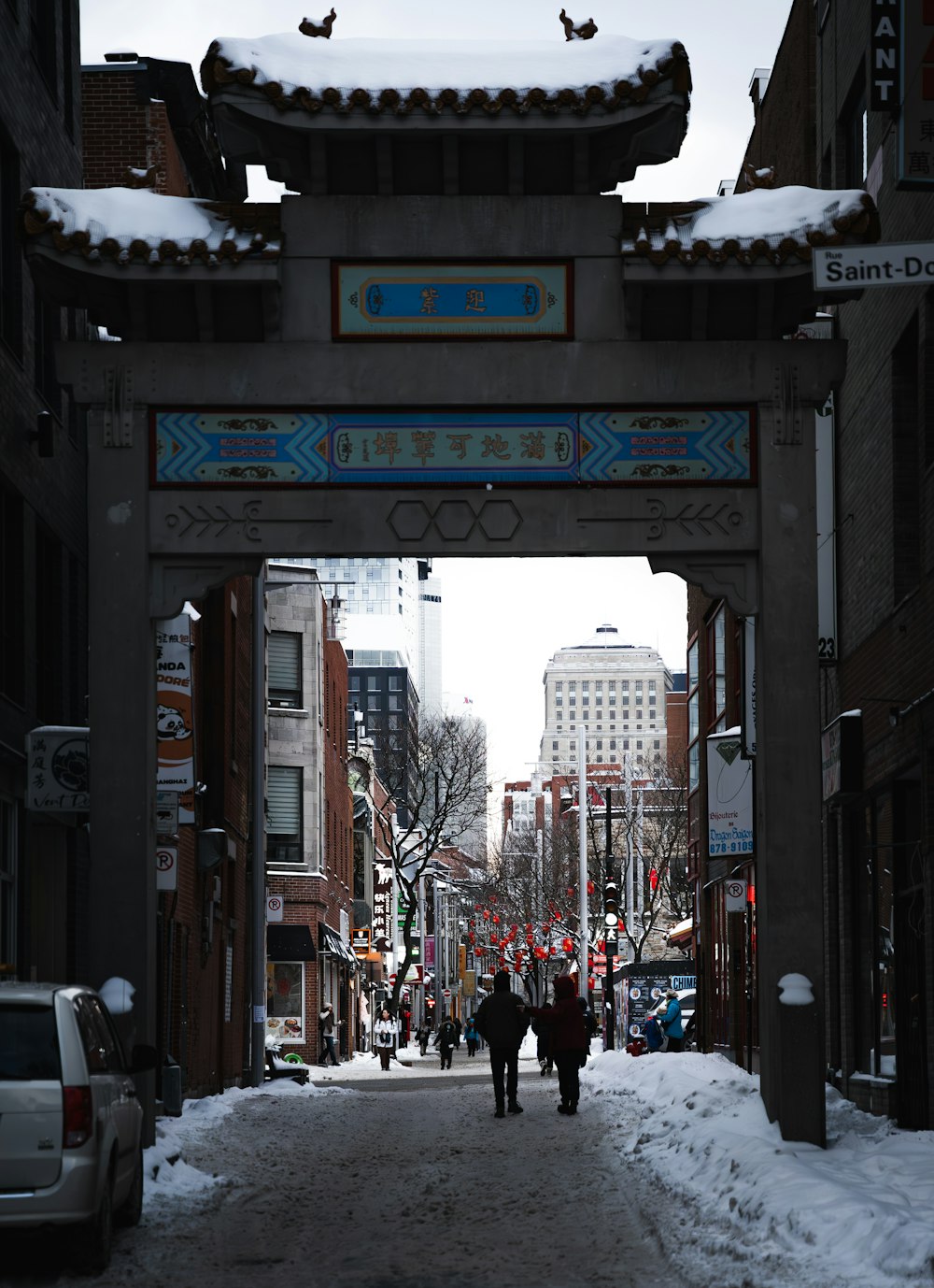 a couple of people walking down a snow covered street