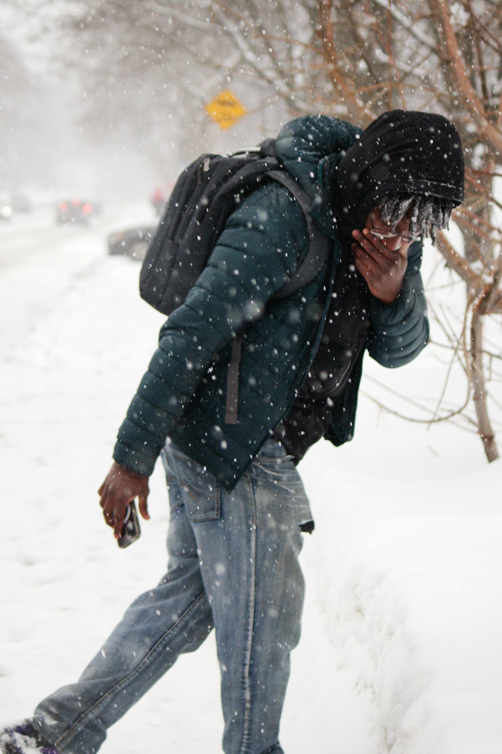 a man walking in the snow talking on a cell phone