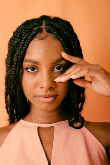 a woman in a pink top holding her hand up to her face