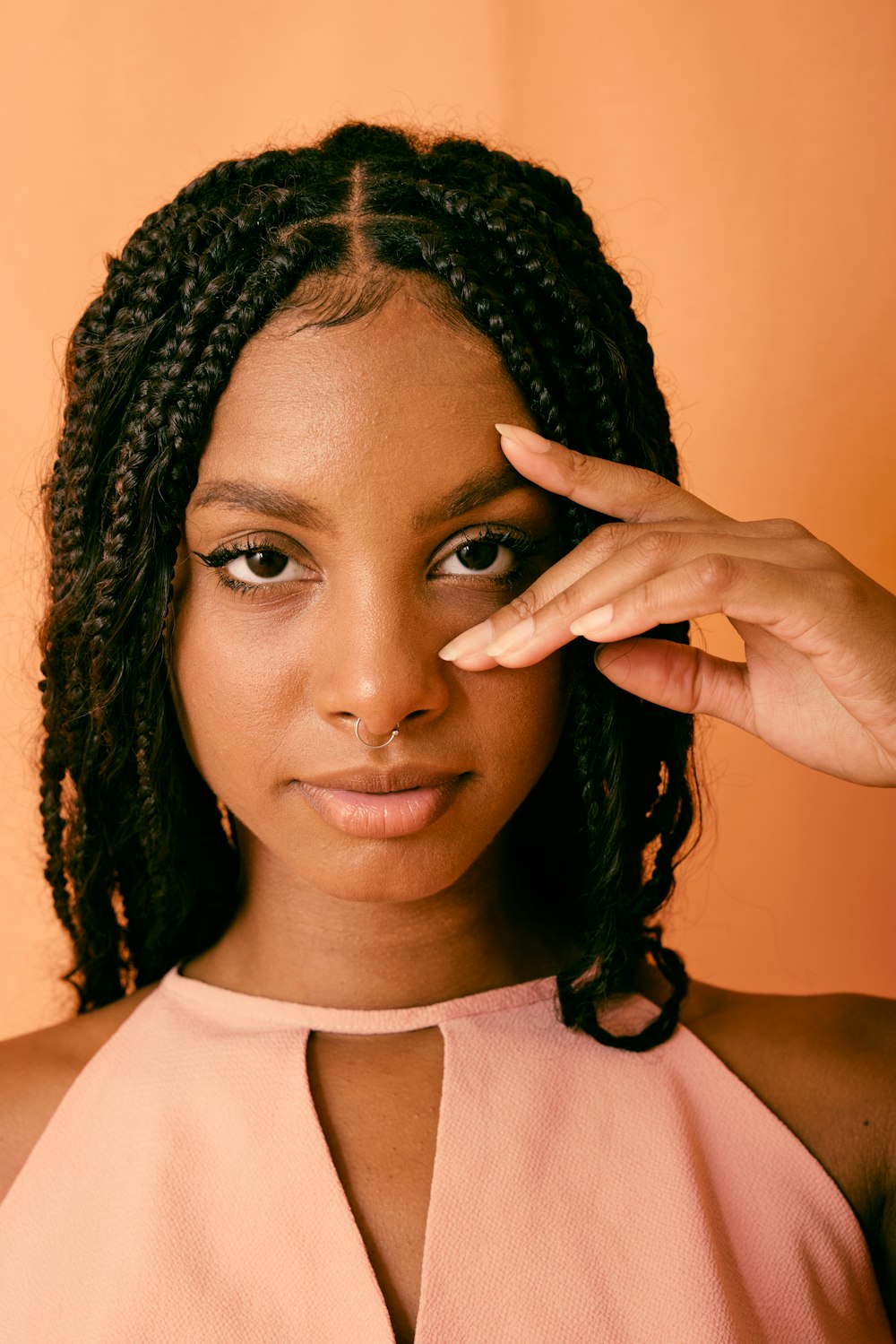 uma mulher de top rosa segurando a mão até o rosto