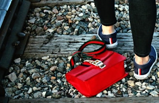 a woman's feet with a red purse and a red purse