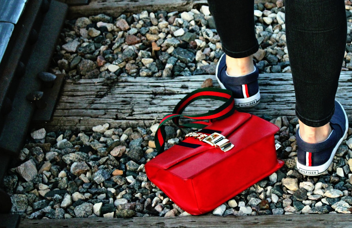 a woman's feet with a red purse and a red purse