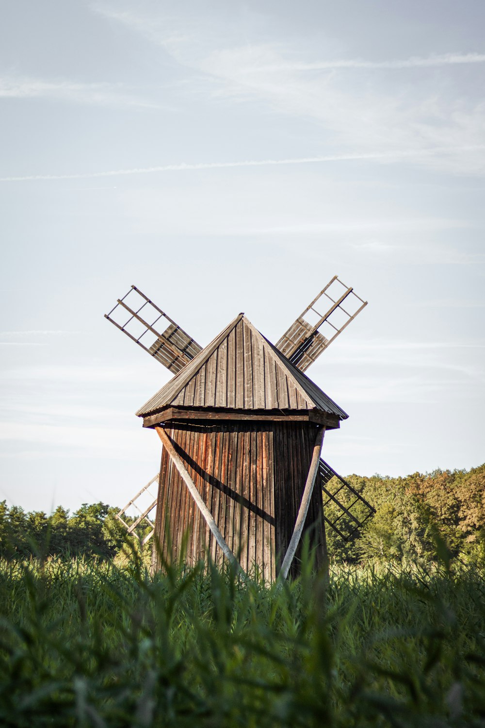 an old wooden windmill in a grassy field