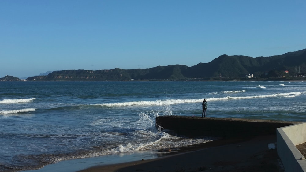 a person standing on a beach next to the ocean