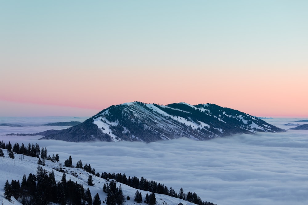 a mountain covered in snow and surrounded by clouds