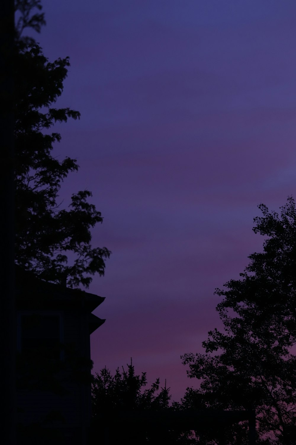 a clock tower is silhouetted against a purple sky