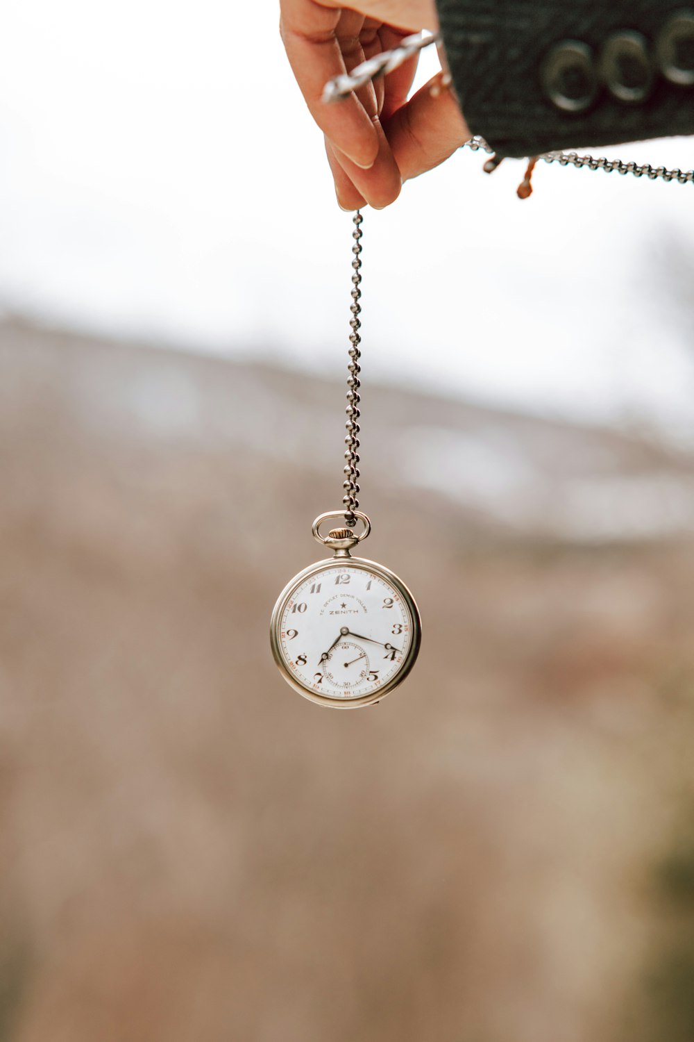 a person holding a small pocket watch in their hand