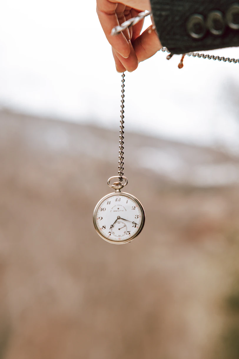 a person holding a small pocket watch in their hand