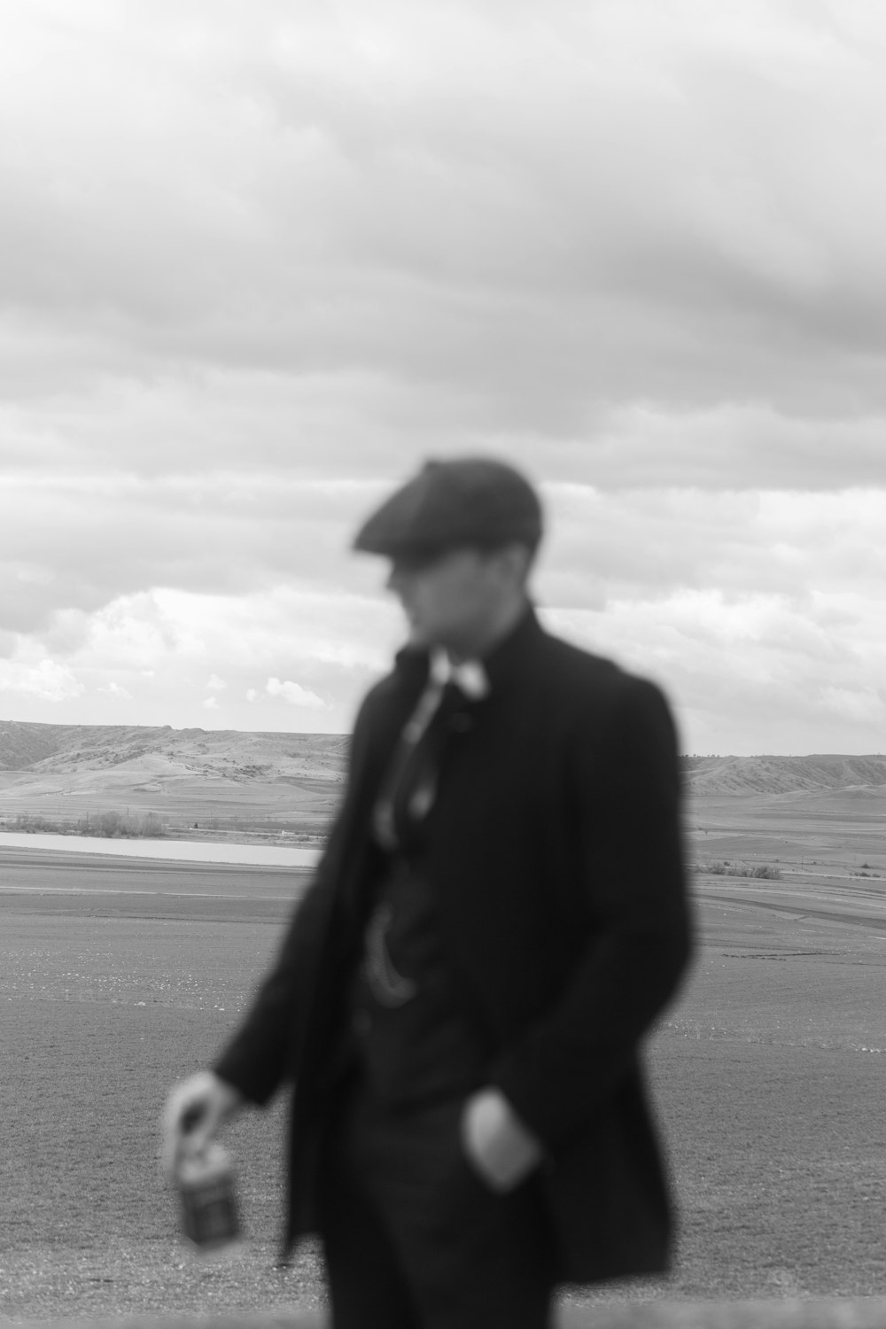 a man in a suit and hat walking on a beach