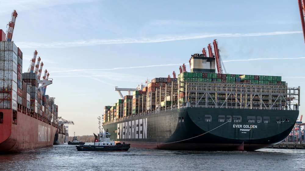 a large cargo ship in the water with a tug boat in front of it