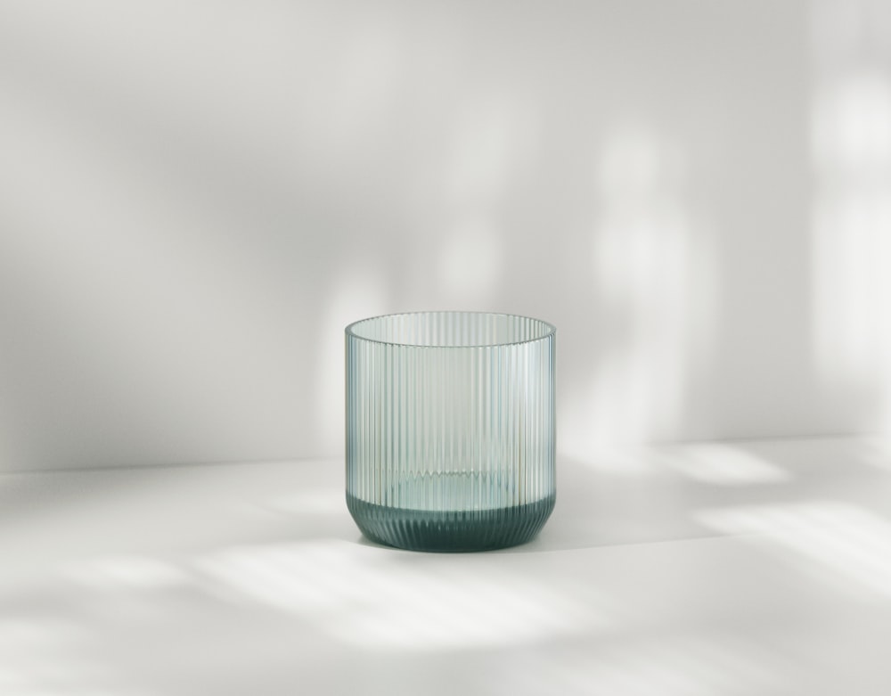 a green glass sitting on top of a white table