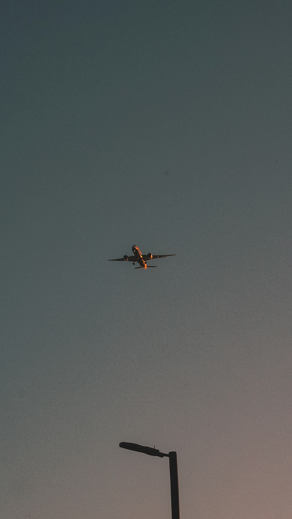 an airplane is flying in the sky above a street light