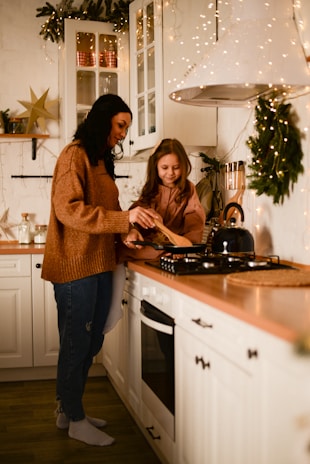a couple of women standing in a kitchen preparing food