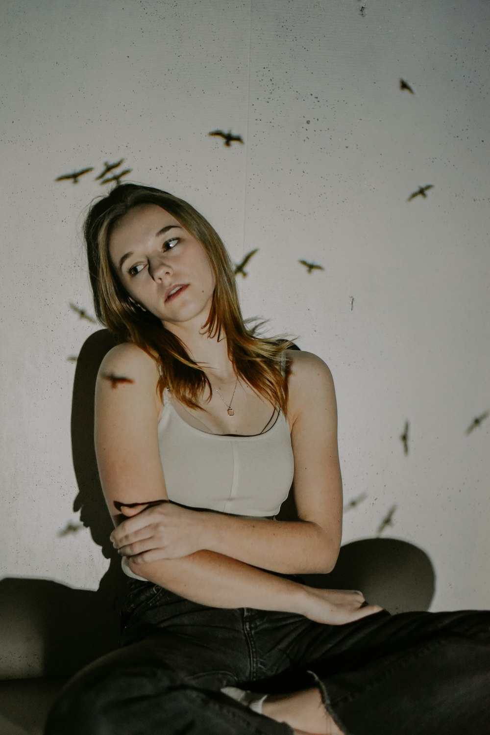 a woman sitting in a chair with birds flying around her