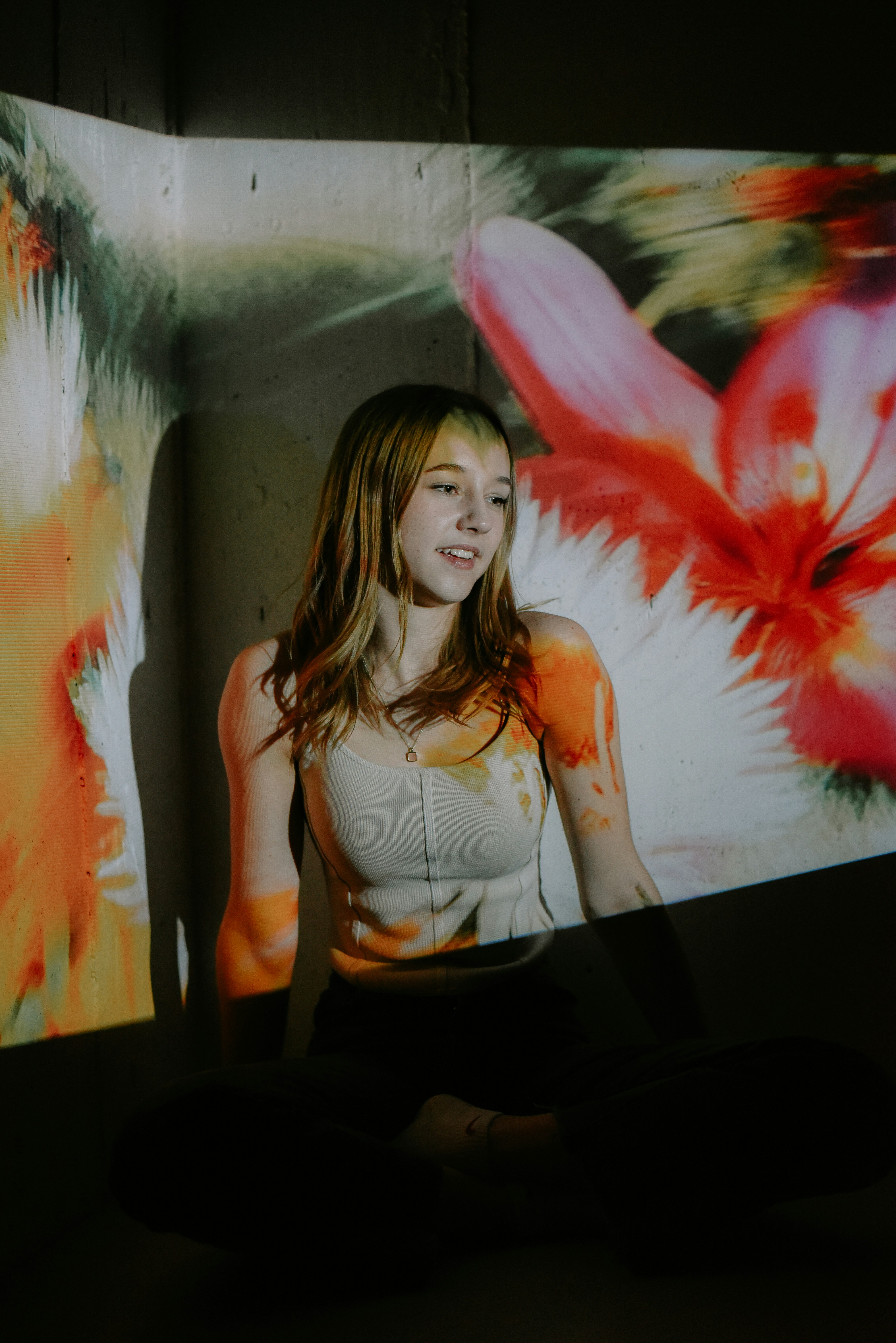 a woman sitting on the floor in front of a painting