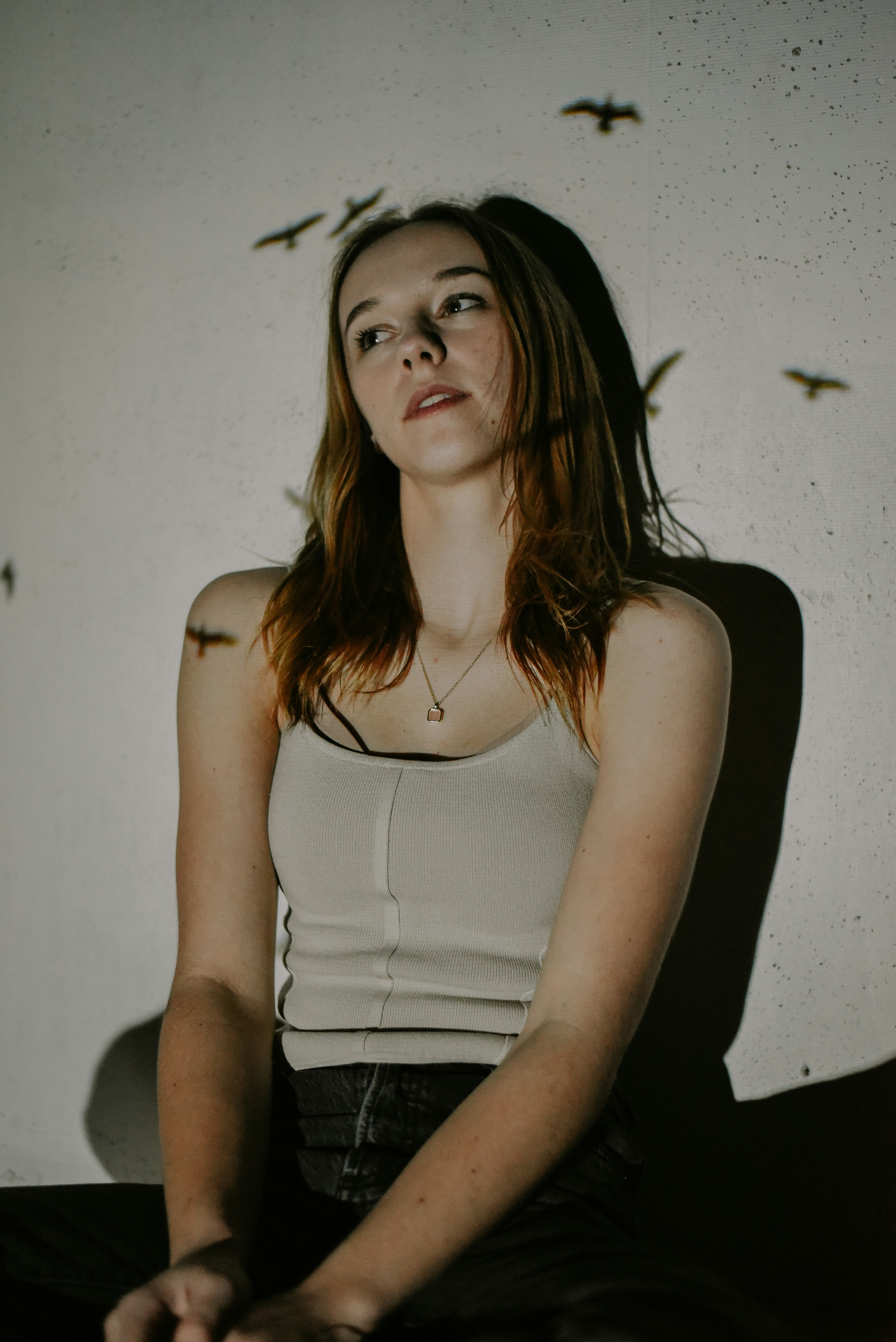 a woman sitting in a chair with birds flying around her