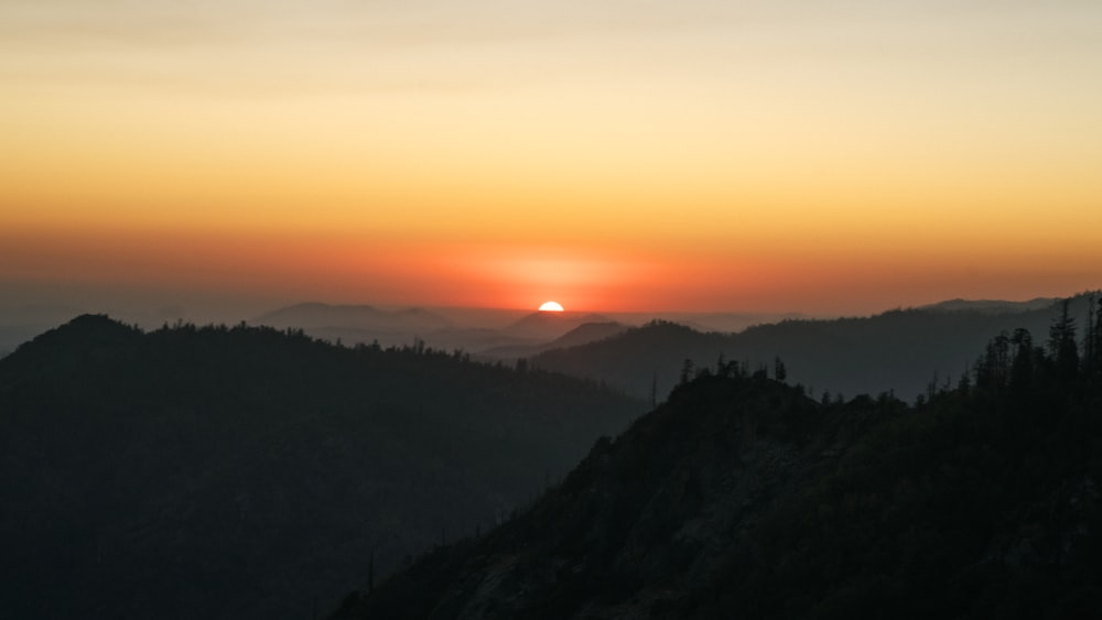 the sun is setting over a mountain range