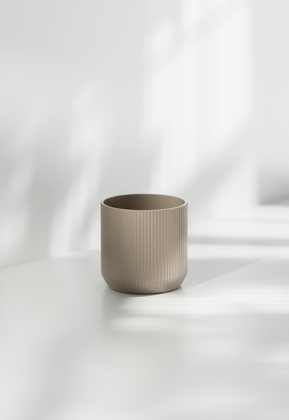 a beige cup sitting on top of a white table
