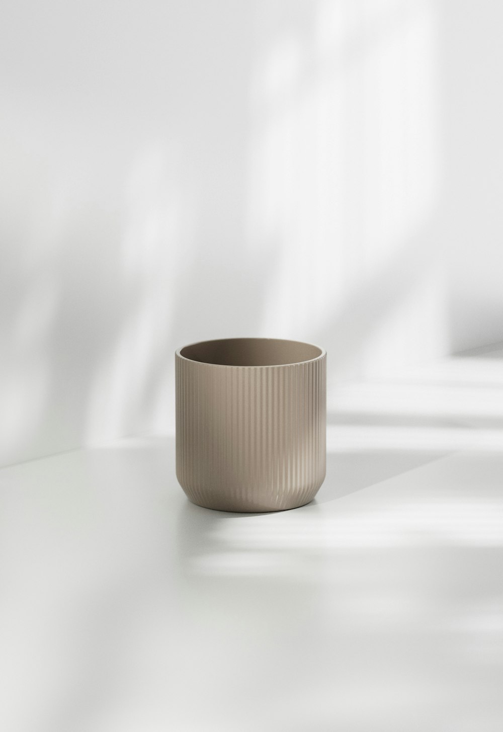 una taza beige encima de una mesa blanca