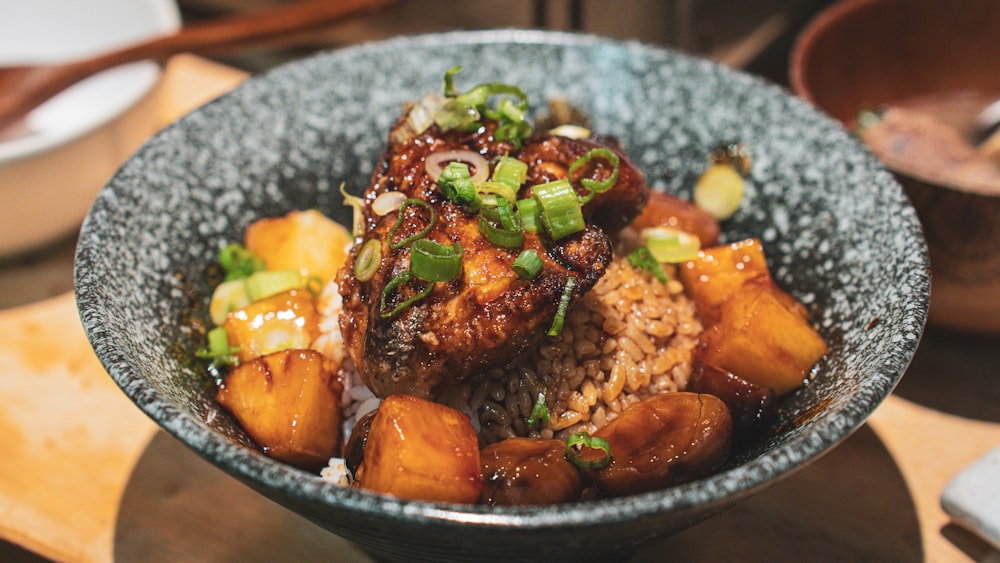 a bowl of food with meat, rice and vegetables